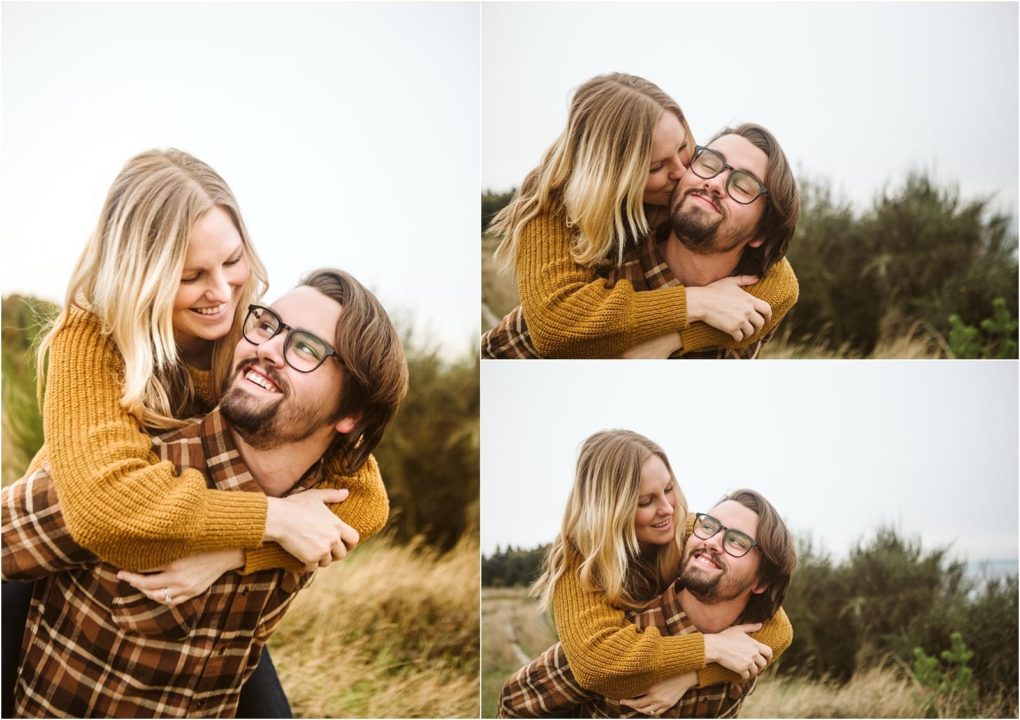 Premier snohomish & seattle wedding photographer | gsquared weddings photography a smiling woman with blonde hair gives a playful piggyback ride to her bearded fiancé in glasses during their snohomish engagement session Both wear cozy autumn sweaters and look happy together in a grassy field | serving snohomish seattle                   & beyond