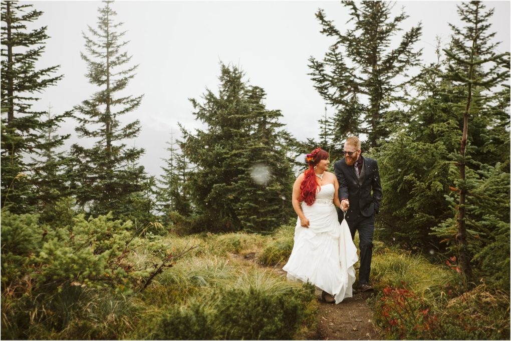 Premier snohomish & seattle wedding photographer | gsquared weddings photography a bride in a white dress and a man in a suit walk together on a forested trail near snohomish surrounded by tall evergreen trees mist and cloudy skiesa perfect seattle wedding engagement moment | serving snohomish seattle                   & beyond