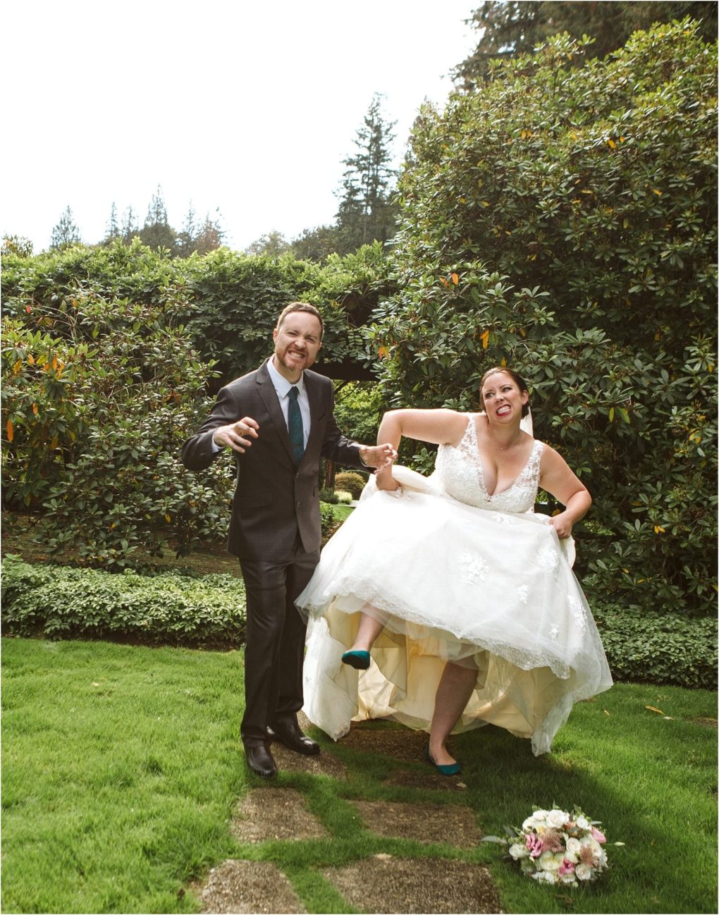 Premier snohomish & seattle wedding photographer | gsquared weddings photography a bride in a white dress playfully lifts her skirt to show blue shoes while smiling next to her groom in a suit Surrounded by lush greenery and trees this snohomish wedding scene captures the joy of a seattle engagement A bouquet lies on the grass | serving snohomish seattle                   & beyond
