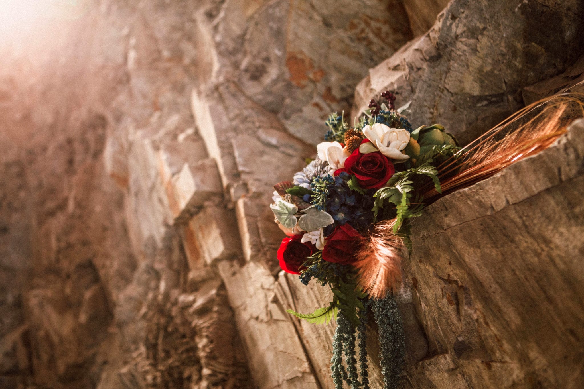 Premier Snohomish & Seattle Wedding Photographer | GSquared Weddings Photography A bouquet of red, white, and purple flowers with greenery rests on a rocky ledge, illuminated by warm sunlight—perfect for a Snohomish or Seattle wedding engagement.                                   | Serving Snohomish, Seattle ,                  & Beyond