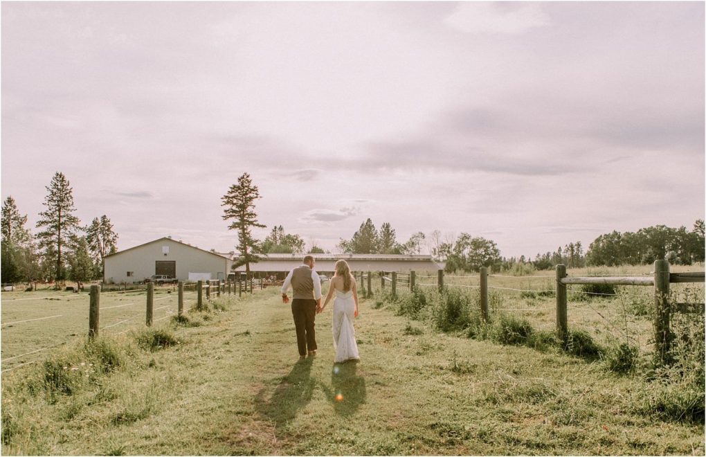 Premier snohomish & seattle wedding photographer | gsquared weddings photography a couple holding hands walks down a grassy path toward a barn on a sunny day surrounded by trees and fenced fieldsa charming snohomish seattle wedding engagement moment | serving snohomish seattle                   & beyond