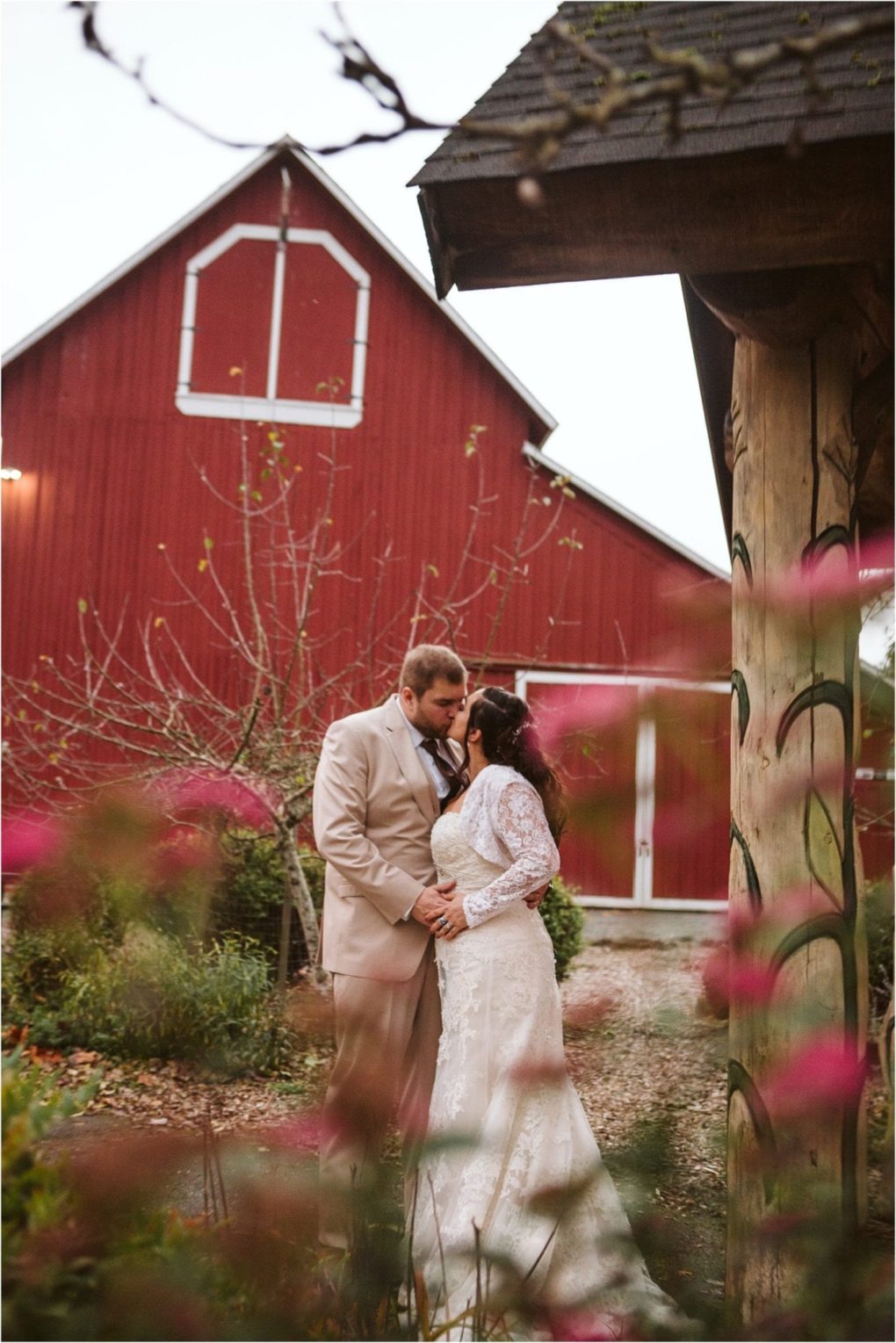 Premier snohomish & seattle wedding photographer | gsquared weddings photography a bride and groom embrace outside near a rustic wooden structure with a red barn in the background Pink flowers and greenery frame this romantic snohomish countryside scene perfect for a seattle wedding or engagement | serving snohomish seattle                   & beyond