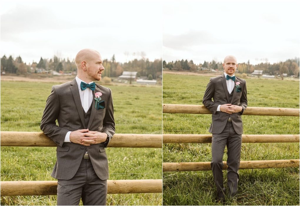 Premier snohomish & seattle wedding photographer | gsquared weddings photography a man in a grey suit with a teal bow tie and pink boutonniere stands by a wooden fence in a grassy field perfect for a snohomish wedding or seattle engagement with trees and houses visible under the cloudy sky | serving snohomish seattle                   & beyond