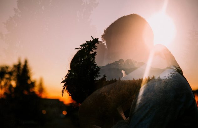 Premier snohomish & seattle wedding photographer | gsquared weddings photography a double exposure image of a couple embracing at sunset with silhouettes of trees and mountains blending into their figures creates a dreamy romantic snohomish wedding scene with warm sunlight in the background | serving snohomish seattle                   & beyond