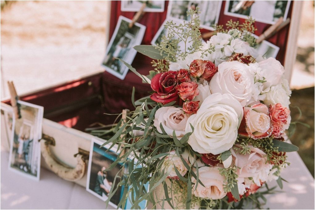 Premier snohomish & seattle wedding photographer | gsquared weddings photography a bouquet of white blush and red roses with greenery sits in front of an open vintage suitcase decorated with hanging blurred photographsperfect for a romantic snohomish seattle wedding engagement | serving snohomish seattle                   & beyond