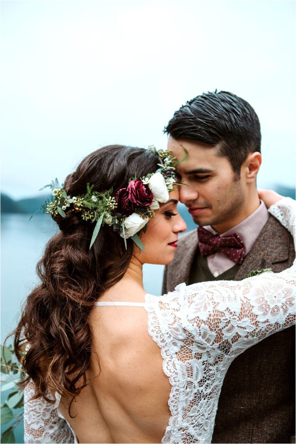 Premier snohomish & seattle wedding photographer | gsquared weddings photography a bride in a lace dress with a floral crown embraces her groom in a tweed suit and bow tie Standing closely together by the water they share a loving gazecapturing the magic of their snohomish seattle wedding engagement | serving snohomish seattle                   & beyond