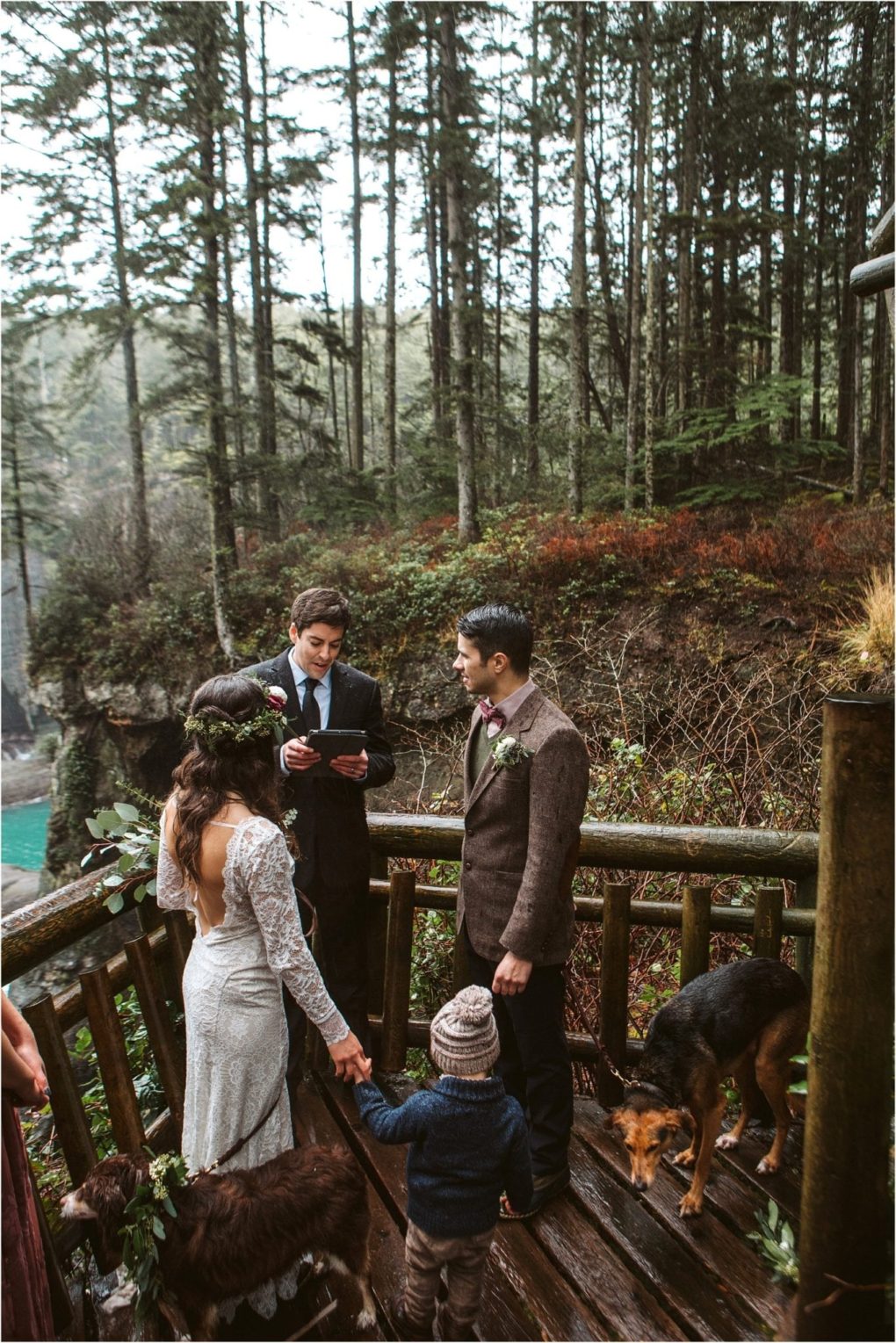 Premier snohomish & seattle wedding photographer | gsquared weddings photography a couple stands on a rustic wooden deck in a forest holding hands with a child during their snohomish wedding Another man reads from a book and two dogs are nearby Forest and water provide a peaceful seattle engagement backdrop | serving snohomish seattle                   & beyond