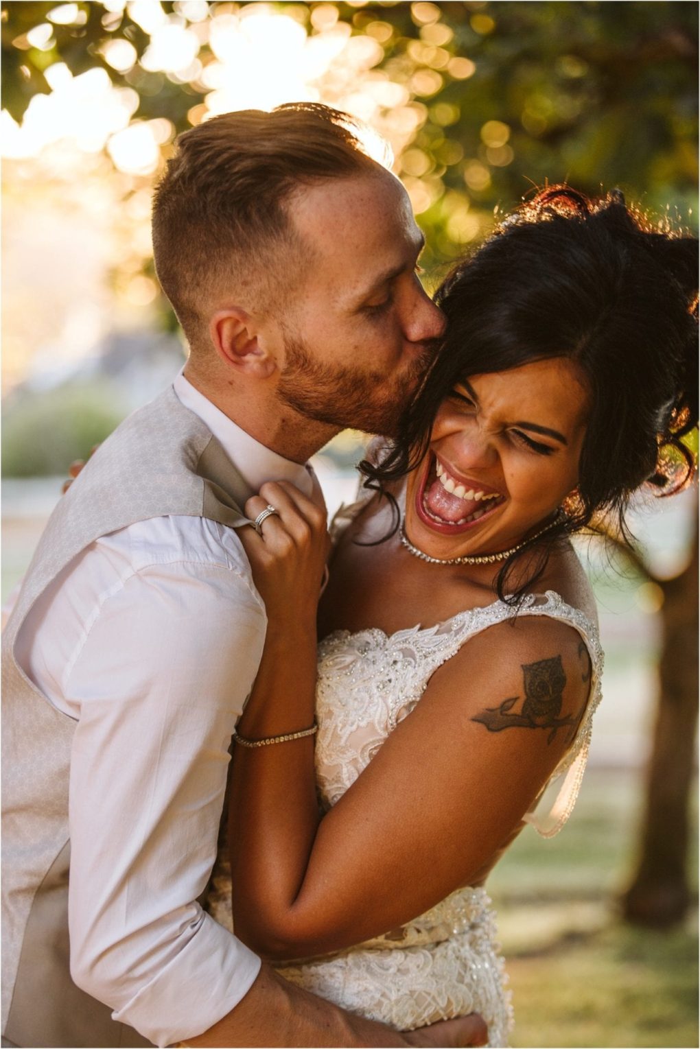 Premier snohomish & seattle wedding photographer | gsquared weddings photography a groom in a light suit kisses his smiling bride on the forehead as she laughs wearing a lace dress and pearl necklace during their snohomish seattle wedding outdoors in warm sunlight | serving snohomish seattle                   & beyond
