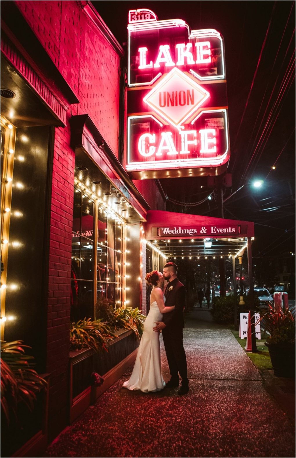 Premier snohomish & seattle wedding photographer | gsquared weddings photography a bride and groom embrace under a glowing neon lake union cafe sign at night with string lights reflecting on the buildinga dreamy seattle wedding sceneand a weddings & events sign above the entrance | serving snohomish seattle                   & beyond