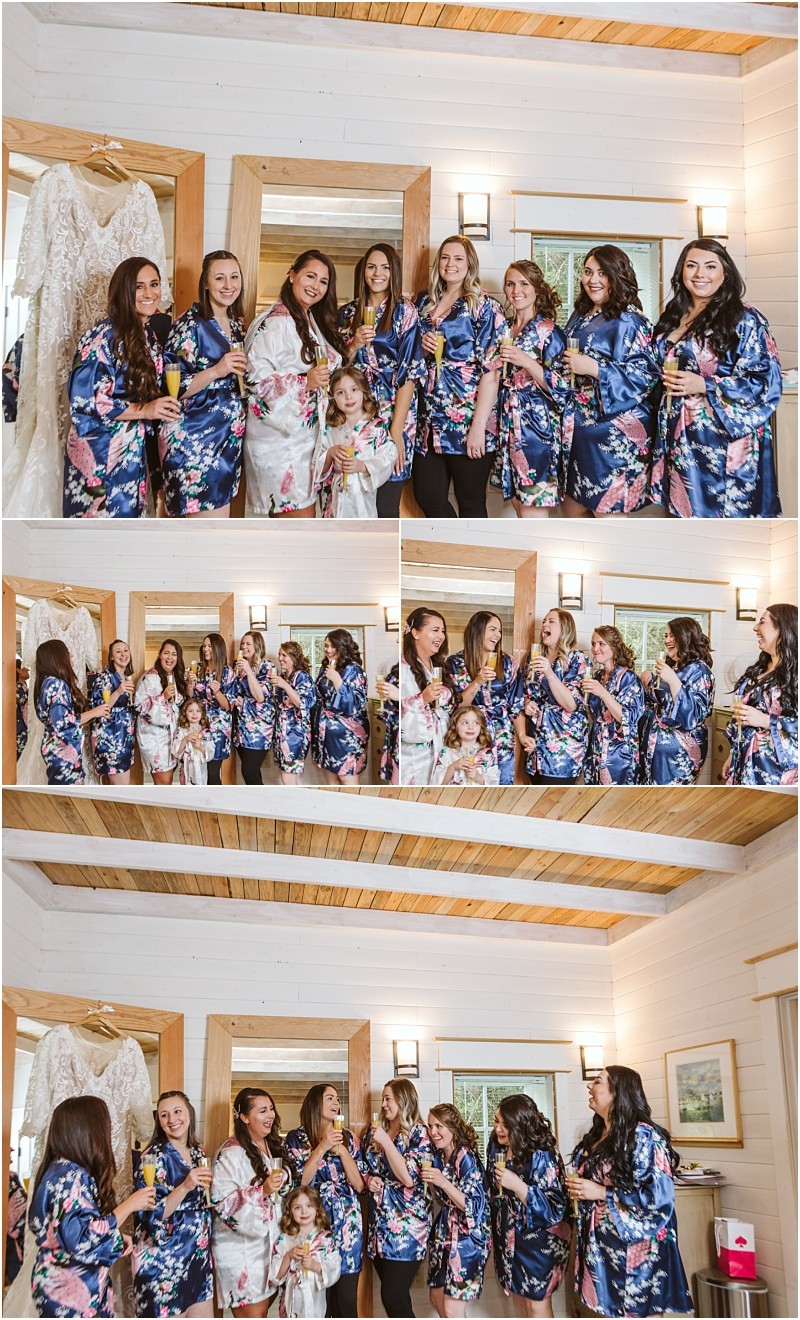 Premier snohomish & seattle wedding photographer | gsquared weddings photography a bride and her bridesmaids all in floral robes smile and toast with drinks in a cozy wooden accented room A white wedding dress hangs in the background capturing a joyful moment before their snohomish seattle wedding | serving snohomish seattle                   & beyond