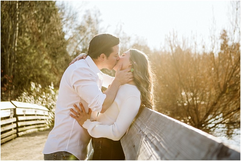 Premier snohomish & seattle wedding photographer | gsquared weddings photography a couple stands on a wooden bridge near snohomish kissing passionately in the sunlight The background features leafless trees and a golden sky creating a romantic atmosphere perfect for a seattle wedding engagement | serving snohomish seattle                   & beyond