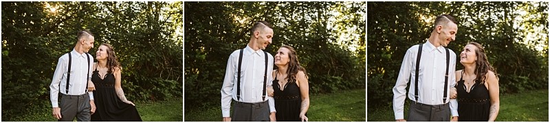 Premier snohomish & seattle wedding photographer | gsquared weddings photography a couple stands outdoors in front of leafy greenery smiling at each other during their snohomish engagement The man wears a light shirt with suspenders and the woman wears a black dress as sunlight filters through the trees behind them | serving snohomish seattle                   & beyond