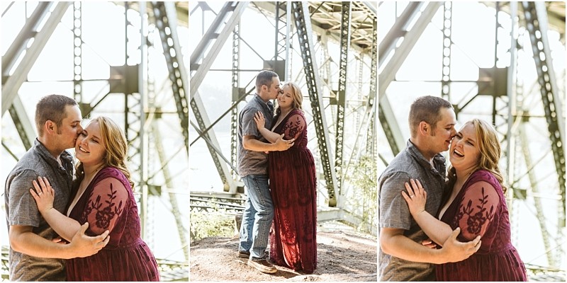 Premier snohomish & seattle wedding photographer | gsquared weddings photography a couple poses affectionately under a large metal bridge near snohomish They hug smile and laugh together as sunlight streams through the beams The woman wears a long burgundy dressperfect for a seattle wedding engagement session | serving snohomish seattle                   & beyond