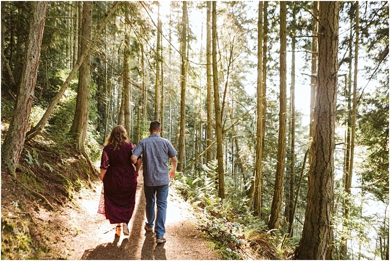 Premier snohomish & seattle wedding photographer | gsquared weddings photography a couple walks hand in hand along a sunlit forest trail near snohomish surrounded by tall trees and greenery Sunlight filters through the branches casting a warm golden glow on their seattle wedding engagement moment | serving snohomish seattle                   & beyond