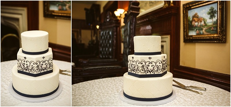 Premier snohomish & seattle wedding photographer | gsquared weddings photography a three tier white wedding cake with navy blue ribbon accents and black ornate detailing sits on a round white tablecloth in an elegant snohomish seattle wedding venue with dark wood furniture and framed paintings | serving snohomish seattle                   & beyond