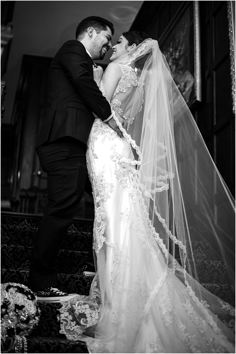 Premier snohomish & seattle wedding photographer | gsquared weddings photography a bride and groom stand close together on a staircase smiling lovingly at each other during their snohomish wedding The bride wears a lace wedding dress with a long veil and the groom is in a suit The black and white photo captures pure joy | serving snohomish seattle                   & beyond