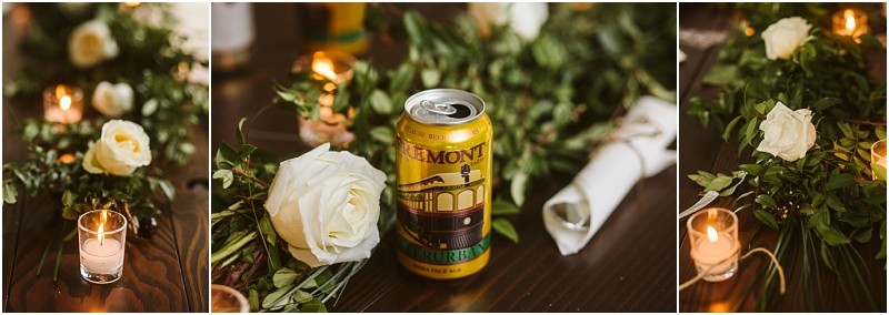 Premier snohomish & seattle wedding photographer | gsquared weddings photography a yellow can of fremont beer sits on a dark wooden table at a seattle wedding surrounded by white roses greenery a lit candle in a glass holder and a rolled napkin | serving snohomish seattle                   & beyond