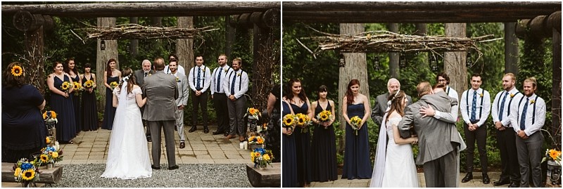 Premier snohomish & seattle wedding photographer | gsquared weddings photography a bride in a white gown stands at an outdoor altar with her father during a snohomish wedding facing the officiant and groom Bridesmaids in navy dresses and groomsmen in suspenders hold sunflower bouquets on either side | serving snohomish seattle                   & beyond