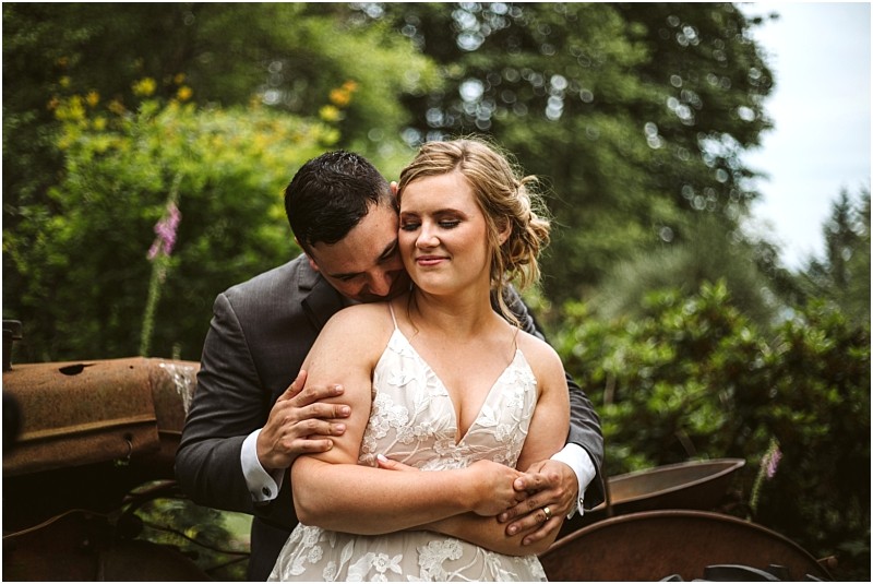 Premier snohomish & seattle wedding photographer | gsquared weddings photography a groom in a dark suit embraces his bride in a white lace dress from behind Surrounded by greenery at their snohomish seattle wedding the bride smiles softly as the groom gently nuzzles her shoulder | serving snohomish seattle & beyond Premier snohomish & seattle wedding photographer | gsquared weddings photography a groom in a dark suit embraces his bride in a white lace dress from behind Surrounded by greenery at their snohomish seattle wedding the bride smiles softly as the groom gently nuzzles her shoulder | serving snohomish seattle & beyond