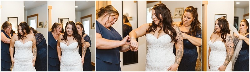 A bride in a white dress is helped by two women in blue dresses as she gets ready in a brightly lit snohomish room adjusting her dress and jewelry surrounded by framed photos on the walls Snohomish wedding photography