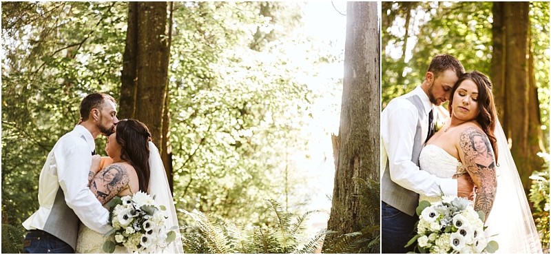 A bride and groom embrace in a sunlit snohomish forest surrounded by greenery The bride holds a bouquet of white flowers and wears a strapless gown with a veil while the groom wears a vest and white shirt Both appear calm and affectionate Snohomish wedding photography