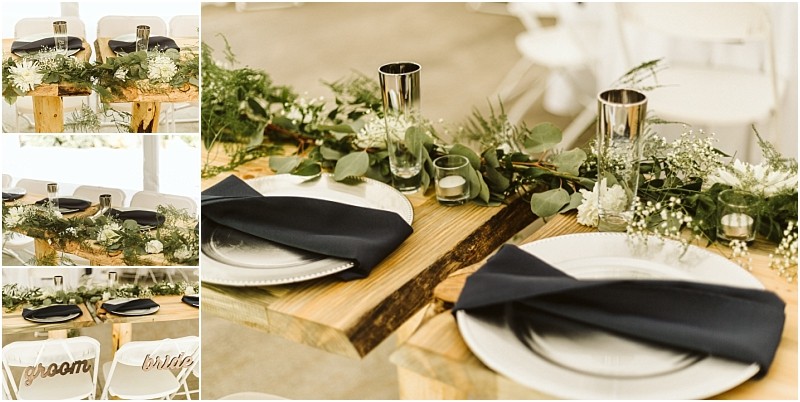 Close up of a rustic wedding table setting in snohomish with greenery white flowers candles black napkins on white plates and metallic cups Nearby white chairs labeled groom and bride are visible Snohomish wedding photography