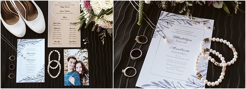 Snohomish wedding invitation suite displayed with white shoes jewelry a couples photo floral arrangements a program rings and pearl accessories all artfully arranged on a dark striped surface Snohomish wedding photography