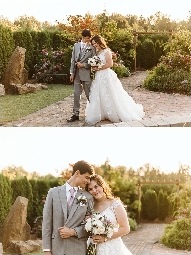 A bride in a white gown and a groom in a gray suit pose together outdoors in a snohomish garden holding hands and a bouquet of white flowers smiling and leaning affectionately against each other Snohomish wedding photography