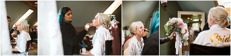 A bride in snohomish gets her makeup done in a bright room sits as an artist applies blush receives her bouquet of pink and white flowers and sits in a chair with bride written on her robe Snohomish wedding photography