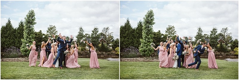 A wedding party poses outdoors in snohomish bridesmaids in pink dresses and groomsmen in navy suits cheer and jump with joy in a green garden setting under a partly cloudy sky Snohomish wedding photography
