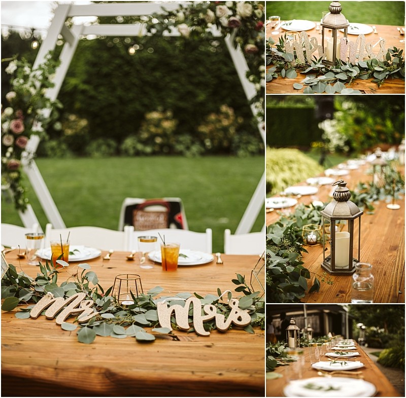A rustic outdoor wedding table in snohomish is decorated with greenery lanterns candles and wooden mr and mrs signs set under a white arch with floral accents in a lush garden setting Snohomish wedding photography