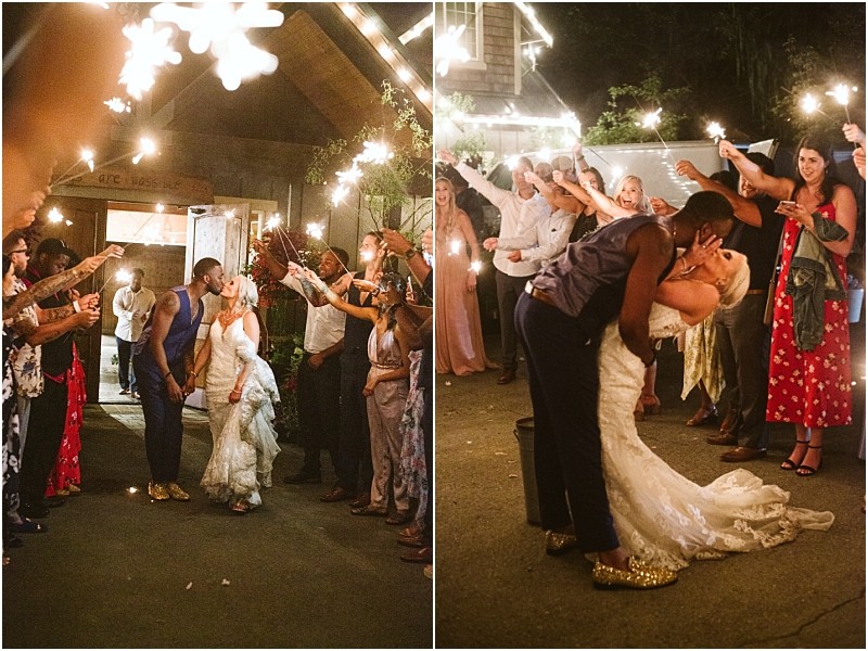 A newlywed couple shares a kiss and a dip outside at night in snohomish surrounded by guests holding sparklers and celebrating under festive lights Snohomish wedding photography
