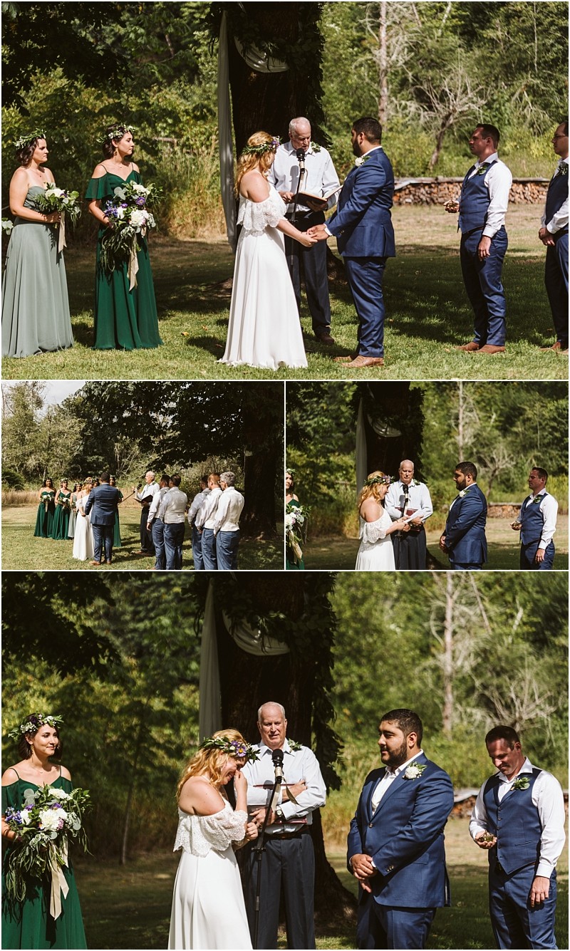 A bride and groom stand with their wedding party and officiant outdoors in lush snohomish greenery The bride wipes her eyes during the ceremony while bridesmaids and groomsmen all in formal attire look on with emotion Snohomish wedding photography