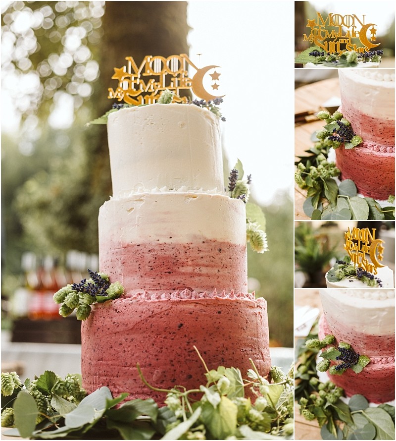A three tiered wedding cake with white and pink ombré frosting decorated with fresh greenery and lavender Perfect for a snohomish celebration the gold topper reads moon of my life my sun and stars adorned with moon and star shapes Snohomish wedding photography