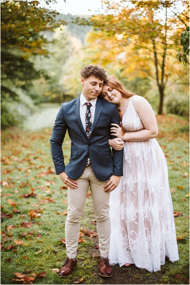 Premier snohomish & seattle wedding photographer | gsquared weddings photography a couple stands outdoors in a park with autumn leaves The woman in a white lace dress rests her head on the mans shoulderboth calm and content during their snohomish seattle wedding engagement session | serving snohomish seattle & beyond Premier snohomish & seattle wedding photographer | gsquared weddings photography a couple stands outdoors in a park with autumn leaves The woman in a white lace dress rests her head on the mans shoulderboth calm and content during their snohomish seattle wedding engagement session | serving snohomish seattle & beyond
