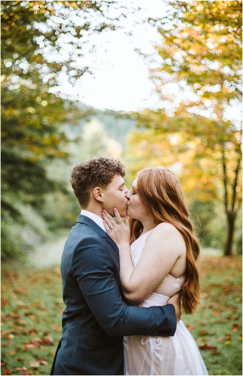 Premier snohomish & seattle wedding photographer | gsquared weddings photography a couple kisses outdoors in a lush green landscape with autumn trees during their snohomish engagement The person on the left wears a dark suit and the person on the right has long red hair and a light dress | serving snohomish seattle & beyond Premier snohomish & seattle wedding photographer | gsquared weddings photography a couple kisses outdoors in a lush green landscape with autumn trees during their snohomish engagement The person on the left wears a dark suit and the person on the right has long red hair and a light dress | serving snohomish seattle & beyond