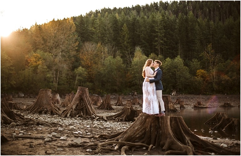 Premier snohomish & seattle wedding photographer | gsquared weddings photography a couple stands on a large tree stump in a rocky dried lakebed near snohomish embracing at sunset with a forested hillside in the backgroundperfect for a seattle wedding engagement session | serving snohomish seattle & beyond Premier snohomish & seattle wedding photographer | gsquared weddings photography a couple stands on a large tree stump in a rocky dried lakebed near snohomish embracing at sunset with a forested hillside in the backgroundperfect for a seattle wedding engagement session | serving snohomish seattle & beyond