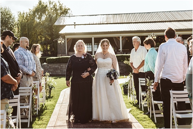 Premier snohomish & seattle wedding photographer | gsquared weddings photography a smiling bride in a white dress walks down an outdoor aisle with an older woman at a snohomish wedding while guests stand and watch on both sides under sunlight | serving snohomish seattle                   & beyond