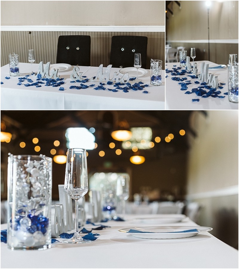 Premier snohomish & seattle wedding photographer | gsquared weddings photography a decorated snohomish wedding reception table with a mr & mrs sign blue rose petals glass vases with white and blue accents champagne flutes and plates set for guests Warm lights glow in the background of this seattle celebration | serving snohomish seattle                   & beyond