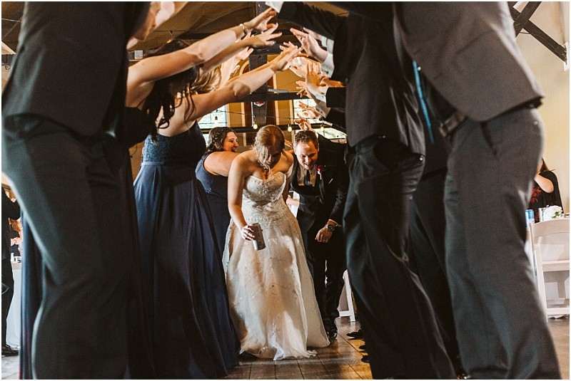 Premier snohomish & seattle wedding photographer | gsquared weddings photography a bride and groom walk under an arch of raised arms formed by their wedding party smiling and celebrating as they enter a snohomish seattle wedding reception The guests wear formal attire and the mood is joyful | serving snohomish seattle                   & beyond
