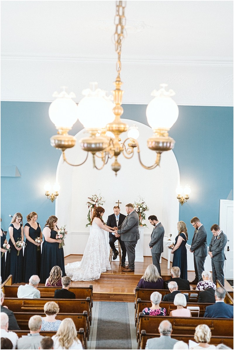 Premier snohomish & seattle wedding photographer | gsquared weddings photography a snohomish wedding ceremony in a church with a bride and groom at the altar surrounded by their bridal party Guests are seated in pews and a chandelier hangs from the ceiling above this beautiful seattle engagement scene | serving snohomish seattle                   & beyond