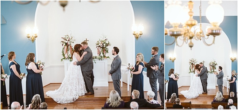 Premier snohomish & seattle wedding photographer | gsquared weddings photography a bride and groom kiss at the altar during a snohomish wedding ceremony in a small chapel surrounded by their navy blue clad wedding party as guests watch from the pews | serving snohomish seattle                   & beyond