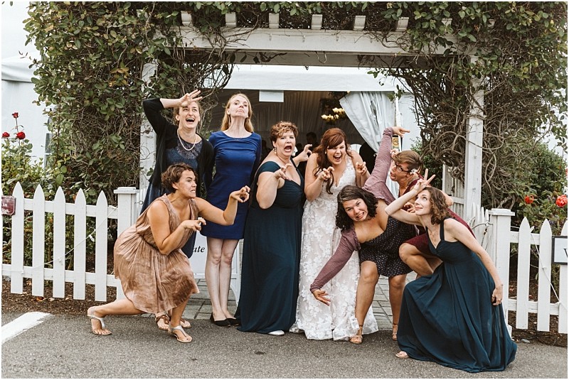 Premier snohomish & seattle wedding photographer | gsquared weddings photography a bride and eight women in dresses pose playfully making silly faces under a vine covered arbor at a snohomish wedding in front of a white picket fence during an outdoor event | serving snohomish seattle                   & beyond