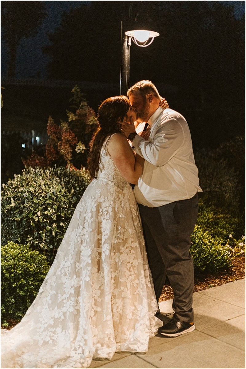 Premier snohomish & seattle wedding photographer | gsquared weddings photography a bride in a lace wedding dress and a groom in a white shirt and dark pants stand close touching foreheads and holding hands under a glowing streetlamp at night in a snohomish gardencapturing true seattle wedding romance | serving snohomish seattle                   & beyond