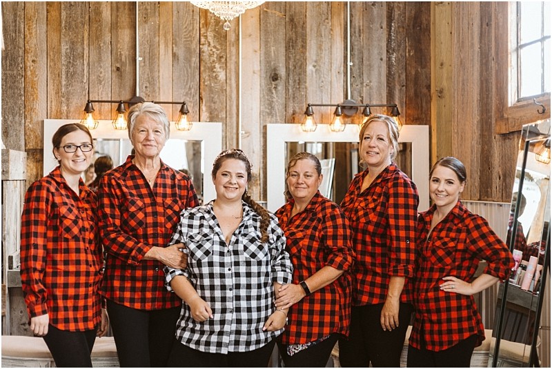 Premier snohomish & seattle wedding photographer | gsquared weddings photography six women stand together smiling in a rustic wood paneled room near seattle Five wear matching red and black plaid shirts while one in the center wears a black and white plaid shirtcapturing a joyful snohomish wedding or engagement moment | serving snohomish seattle                   & beyond