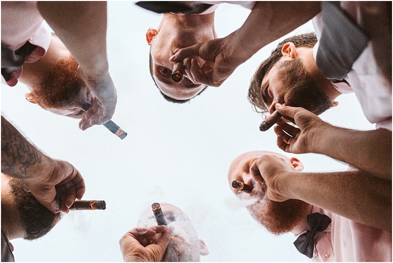 Premier snohomish & seattle wedding photographer | gsquared weddings photography a group of men seen from below forming a circle and smoking cigars together with the sky as the backgroundcapturing a candid moment at a snohomish seattle wedding engagement | serving snohomish seattle                   & beyond