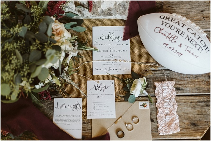 Premier snohomish & seattle wedding photographer | gsquared weddings photography flat lay of snohomish wedding items invitation suite rsvp card note on gifts lace garter rings in a box bouquet boutonniere and a signed football labeled great catch Youre next Featuring seattle engagement details | serving snohomish seattle                   & beyond