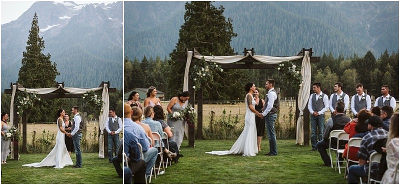 Premier snohomish & seattle wedding photographer | gsquared weddings photography a bride and groom stand under a flower adorned wooden arch during an outdoor snohomish wedding ceremony surrounded by mountains trees their wedding party and seated guests | serving snohomish seattle                   & beyond