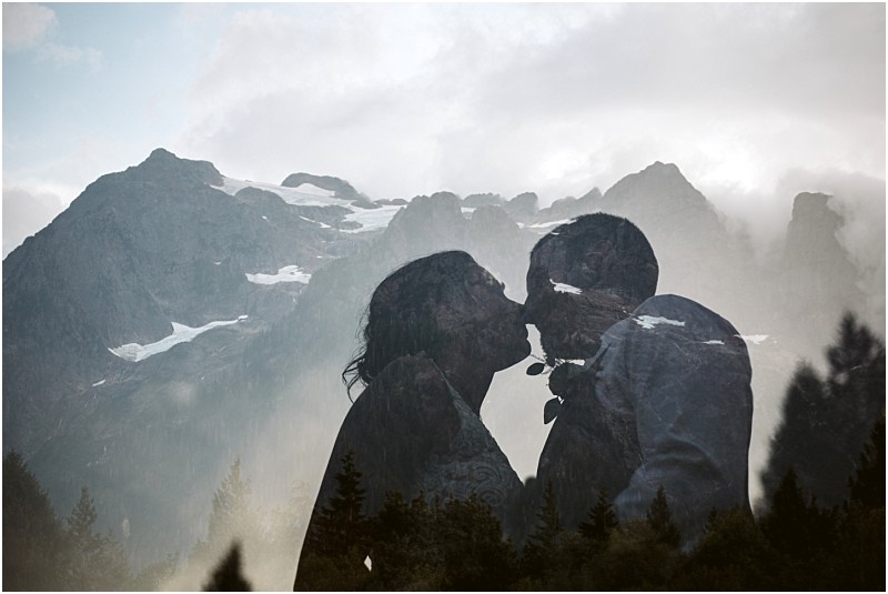 Premier snohomish & seattle wedding photographer | gsquared weddings photography a double exposure photo of a couple about to kiss holding a flower between them with misty snow topped mountains and pine trees in the background capturing the romantic spirit of a snohomish seattle wedding engagement | serving snohomish seattle                   & beyond
