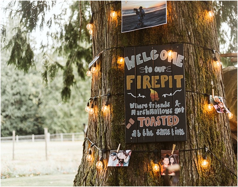 Premier snohomish & seattle wedding photographer | gsquared weddings photography a tree decorated with string lights photos and a sign that reads welcome to our firepit Where friends & marshmallows get toasted at the same time  the perfect snohomish or seattle wedding or engagement backdrop set in a grassy field with fencing | serving snohomish seattle                   & beyond